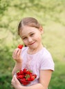 Portrait of Happy cute little girl is eating strawberries at summer day. Soft focused. Vertical Royalty Free Stock Photo