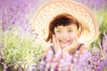 Portrait of happy cute little girl with haircut in big summer hat in lavender field with purple flowers around in sunny summer Royalty Free Stock Photo