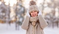 Portrait of happy cute little girl in knitted hat and warm clothes standing in snowy winter park Royalty Free Stock Photo