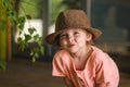 Portrait of happy cute little girl in rural style brown hat and muslin clothes on green background in a summer day Royalty Free Stock Photo