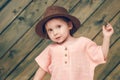 Portrait of happy cute little girl in rural style brown hat and muslin clothes on wooden background in a summer day Royalty Free Stock Photo