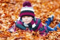 Portrait of happy cute little kid boy with autumn leaves background in colorful clothing. Funny child having fun in fall Royalty Free Stock Photo