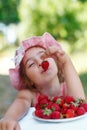 Portrait of Happy cute preteen girl is eating strawberries at summer day. Soft focused