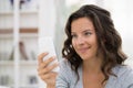 Portrait of happy cute woman with mobile phone sitting on couch Royalty Free Stock Photo