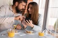 Portrait of happy cute young couple looking at phone and smiling while eating and sitting in a cafe. Joyful couple using Royalty Free Stock Photo