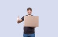 Portrait of happy delivery man holding a box package and showing thumbs up. Delivery man with a parcel  showing thumb up for Royalty Free Stock Photo