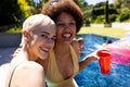 Portrait of happy diverse female friends having pool party, embracing and smiling in garden Royalty Free Stock Photo