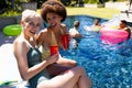 Portrait of happy diverse female friends having pool party, embracing and smiling in garden Royalty Free Stock Photo