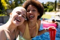 Portrait of happy diverse female friends having pool party, embracing and smiling in garden Royalty Free Stock Photo