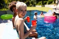 Portrait of happy diverse female friends having pool party, holding cups and smiling in garden Royalty Free Stock Photo