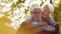 Portrait of happy elderly Caucasian couple woman hugs her husband from the back both smiling man looking down, woman Royalty Free Stock Photo