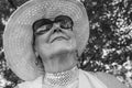 Portrait of a happy elderly woman 65 - 70 years old in a straw hat on the background of nature, closeup. Black and white Royalty Free Stock Photo