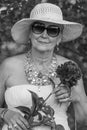 Portrait of a happy elderly woman 65 - 70 years old in a straw hat on the background of nature, closeup. Black and white Royalty Free Stock Photo