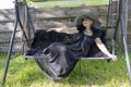 Portrait of a happy elderly woman 65 - 70 years old in a straw hat resting on a swing in the garden, closeup Royalty Free Stock Photo