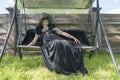 Portrait of a happy elderly woman 65 - 70 years old in a straw hat resting on a swing in the garden, closeup Royalty Free Stock Photo