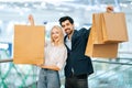 Portrait of happy elegance young couple holding shopping paper bags with purchases and looking at camera, standing in Royalty Free Stock Photo