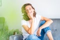 Portrait of happy emotional beautiful young girl woman in jeans couch at home, charming face and smile