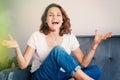 Portrait of happy emotional beautiful young girl woman in jeans couch at home, charming face and smile