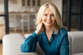 Portrait of happy european mature woman posing smiling to camera, sitting resting on couch at home in modern living room Royalty Free Stock Photo