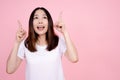 Portrait of a happy excited asian woman standing and pointing two fingers up at copy space isolated over pink background Royalty Free Stock Photo