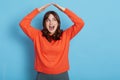 Portrait of happy excited girl wearing orange sweater feeling safe, confident under house roof gesture, dreaming of home, looking Royalty Free Stock Photo