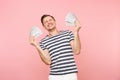 Portrait of happy excited young man in striped t-shirt holding bundle lots of dollars, cash money, ardor gesture on copy