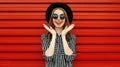 Portrait happy excited young woman wearing a black round hat and sunglasses on red wall Royalty Free Stock Photo