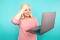 Portrait of happy exited abult lady with laptop isolated over the blue studio.