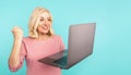 Portrait of happy exited abult lady with laptop isolated over the blue studio.