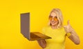 Portrait of happy exited abult lady with laptop isolated over the yellow studio.