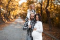 Portrait of happy family on background of golden park in autumn day. Father, daughter and pregnant mother Royalty Free Stock Photo