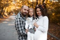 Portrait of happy family on background of golden park in autumn day. Father, daughter and pregnant mother Royalty Free Stock Photo