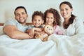 Portrait of a happy family in bed. Smiling hispanic family resting in bed. Parents bonding with their children at home Royalty Free Stock Photo