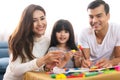 Portrait of happy family daughter girl is learning to use colorful play dough blocks toy together with parent. Royalty Free Stock Photo