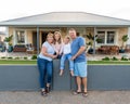 Portrait of Happy family of four embracing and smiling in front of new dream home Royalty Free Stock Photo