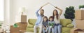 Portrait of happy family with kids sitting at home on sofa holding cardboard roof over their heads. Royalty Free Stock Photo