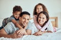 Portrait of happy family with little kids lying on the bed at home. Smiling couple bonding with their son and daughter Royalty Free Stock Photo