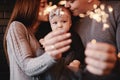 Portrait of happy family, mom, dad and baby girl with sparklers and light. family in anticipation of Christmas. selective photo Royalty Free Stock Photo