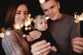 Portrait of happy family, mom, dad and baby girl with sparklers and light. family in anticipation of Christmas. selective photo Royalty Free Stock Photo