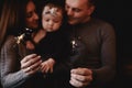 Portrait of happy family, mom, dad and baby girl with sparklers and light. family in anticipation of Christmas. selective photo Royalty Free Stock Photo
