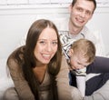 Portrait of happy family, mom and dad playing with their son in bed Royalty Free Stock Photo