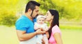 Portrait of happy family, mother and father kissing baby outdoors in summer park Royalty Free Stock Photo