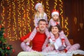 Portrait of a happy family in pajamas and santa claus hats sitting in the bedroom on the bed Royalty Free Stock Photo