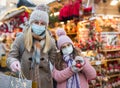 Portrait of happy family in protective masks after shopping for gifts - daughter hugs mom at market