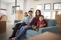 Portrait Of Happy Family Resting On Sofa Surrounded By Boxes In New Home On Moving Day Royalty Free Stock Photo