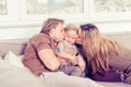 Portrait of happy family sitting on the sofa and playing. Parents kissing their baby son Royalty Free Stock Photo