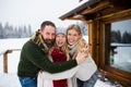 Portrait of happy family with small daughter outdoors in winter holiday cottage, looking at camera. Royalty Free Stock Photo