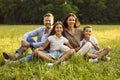 Portrait of happy family with son and daughter sitting in the summer park and looking at camera. Royalty Free Stock Photo