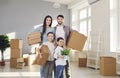 Portrait of happy family standing in their new apartment and holding cardboard boxes Royalty Free Stock Photo