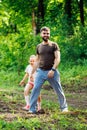 Portrait of happy family walking in park forest around trees, having fun. Little daughter keeping tight hold of father. Royalty Free Stock Photo
